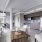 Spacious and well lit living room with wood floors and a large window with access to the kitchen